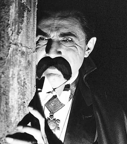 Dracula with Bela Lugosi holding a fake mustache with his nosetrum.